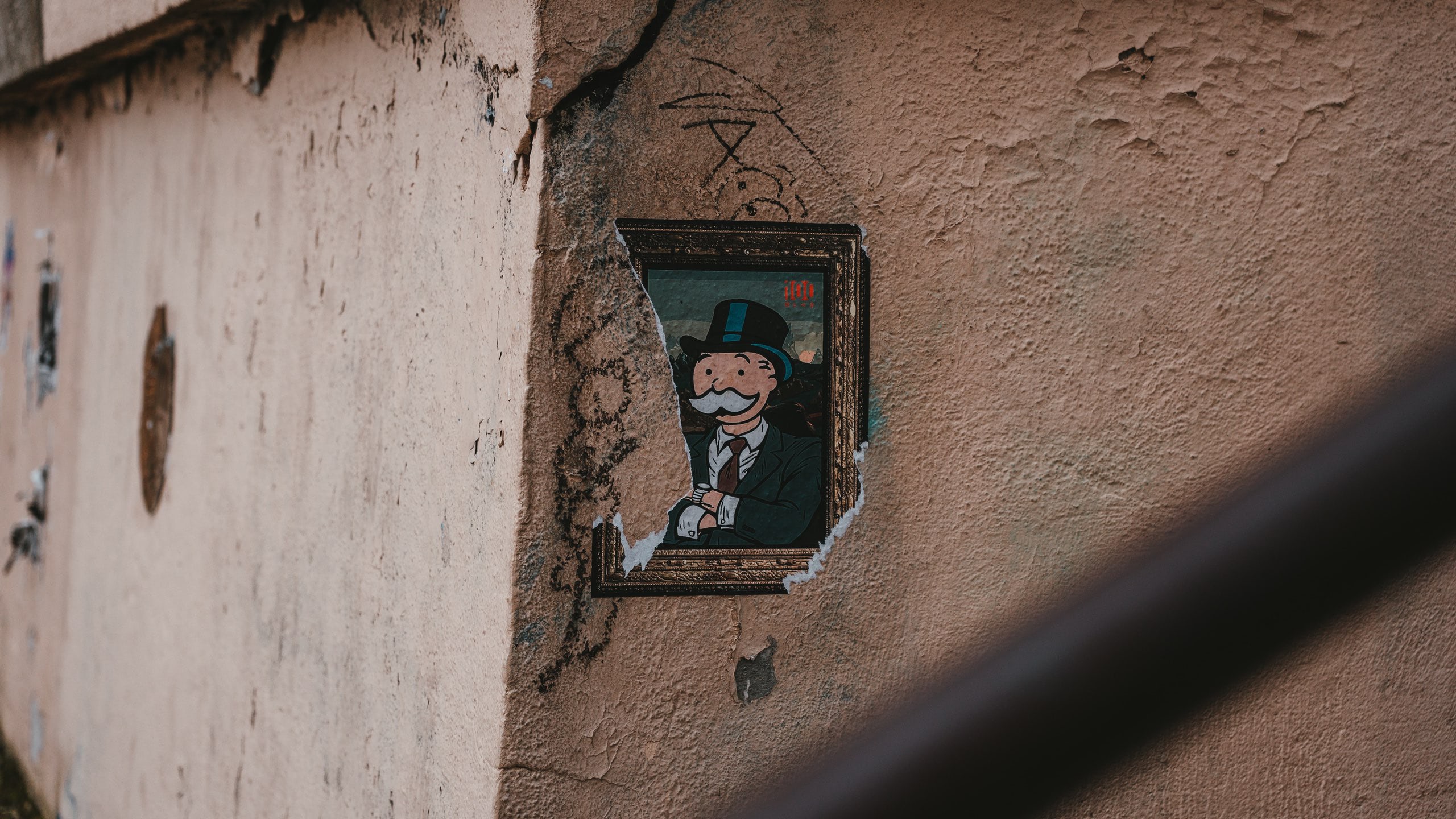 Cracked wall with a piece of art showing the monopoly man