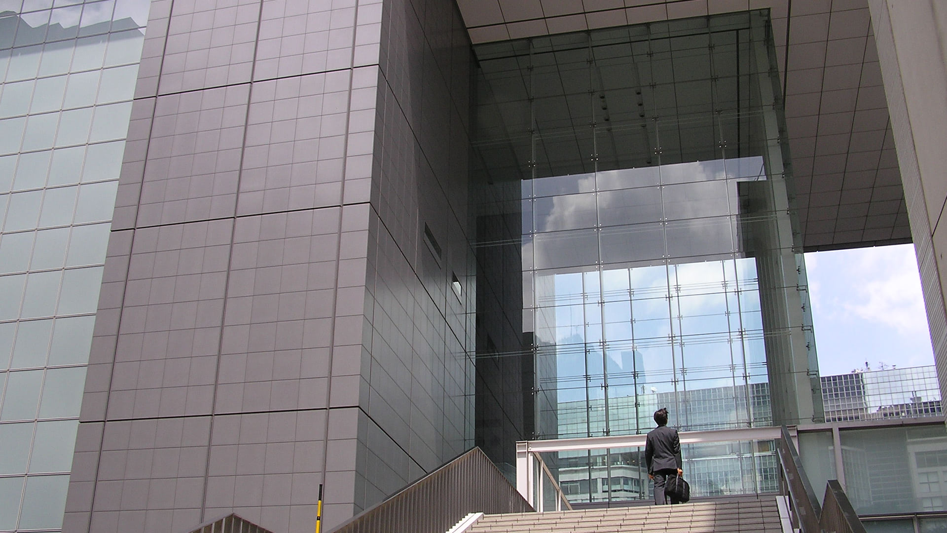 Man standing at top of stairs looking at large building entrance