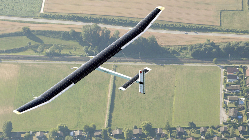 Aerial photo of a solar powered plane flying over fields.